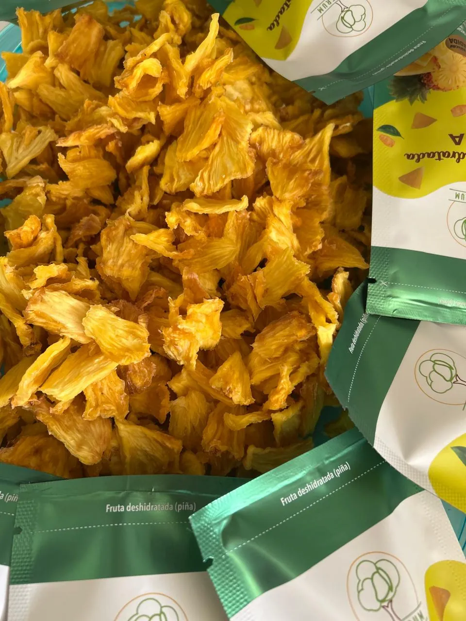 Trozos de piña deshidratada junto a bolsas Natufrum